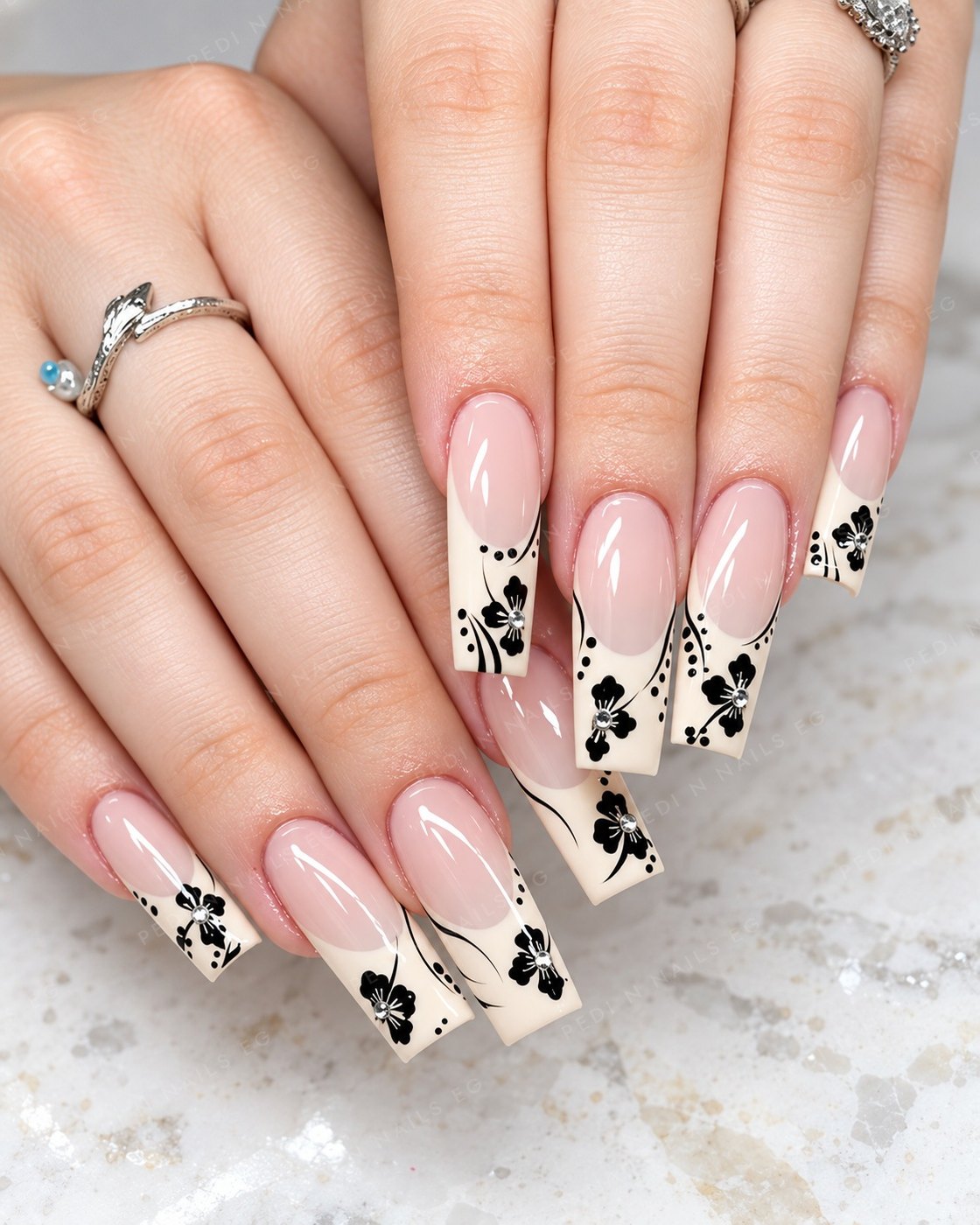 Long square cream French tips with black floral art and crystals