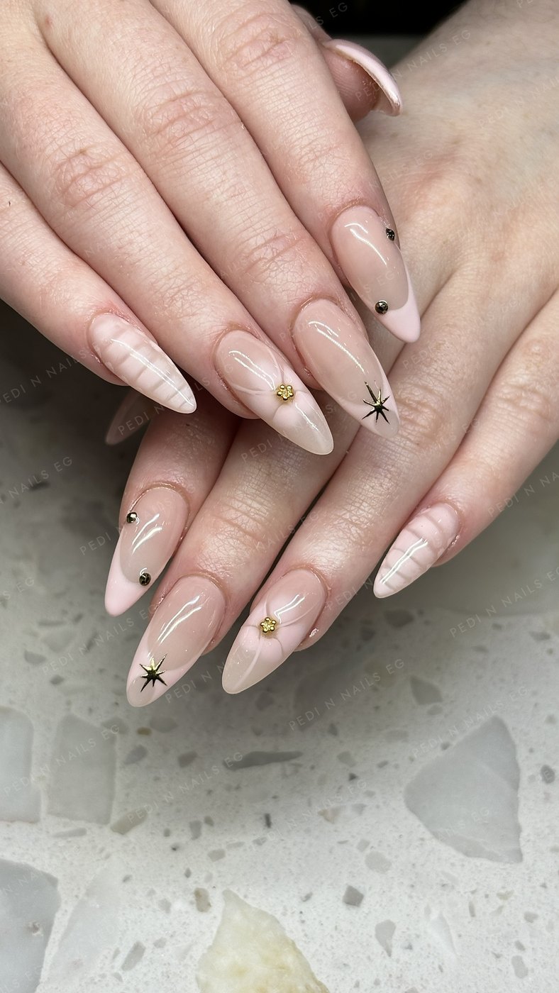 Soft pink almond nails with gold star and flower charms